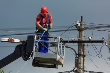 Electrician on a pole deals with wires and cables
