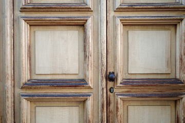 Close-up front view of old white painted rough wooden door with black steel doorknob. 