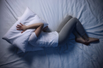 Young woman suffering from insomnia in bed, top view