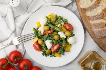Delicious salad with pesto sauce, ingredients and fork on white marble table, flat lay