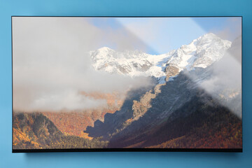 TV screen with mountain landscape on light blue wall