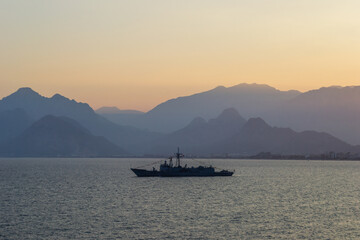 Turkey military warship on sunset with mountains on the background