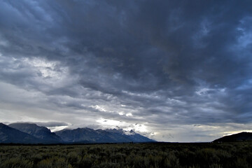 View up Snake River Valley with darkening skies and rain in the distance. Storm clouds shroud the Tetons, Wyoming 