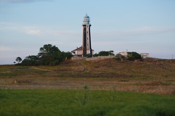 Fototapeta na wymiar Lighthouse for ocean on island and field