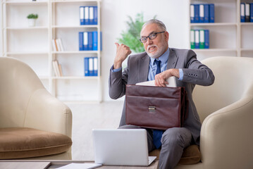 Old male employee sitting on arm-chair