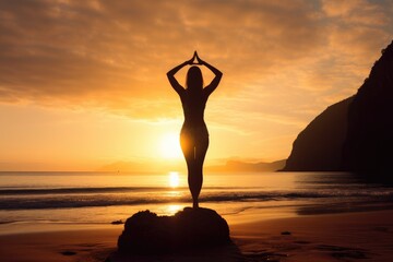 A young woman practicing yoga on the beach at sunset