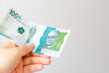 Hand holds a Colombian bill of one hundred thousand pesos, good economy, financial stability