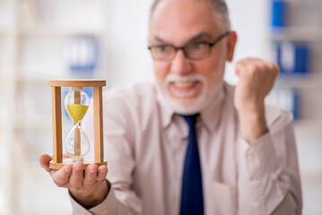 Old male employee in time management concept