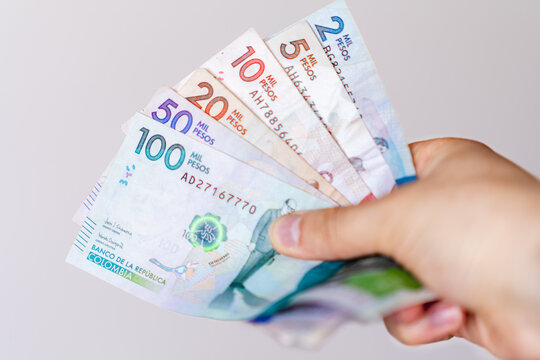 Photograph of Hand holding different Colombian banknotes of different denominations
