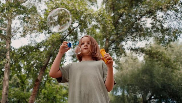 portrait beautiful cute little girl blowing soap bubbles in city park happy carefree childhood