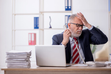Fototapeta premium Old male employee and too much work in the office