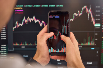 Investor trader broker analyzing financial crypto stock trade invest market on smartphone checking risk digital data in mobile app bank shares, doing charts analysis holding cell phone. Over shoulder.
