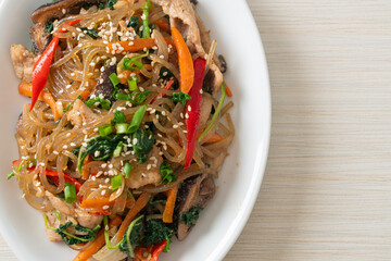japchae or stir-fried Korean vermicelli noodles with vegetables and pork topped with white sesame