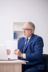 Old male employee working in the office