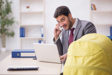 Young male employee looking after newborn at workplace