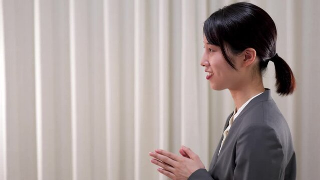 ジェスチャーを交えて熱心に話をするスーツ姿のビジネスウーマンの横顔