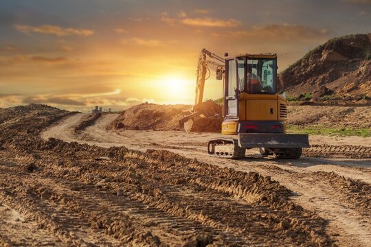 Crawler excavator working on a construction site at sunset
