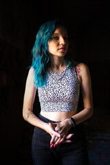 Portrait of a young beautiful girl with long blue hair in a low key on a dark background.