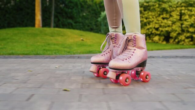 Close up shot of young woman riding quad rollers skates in city. Happy riding retro rollerskates