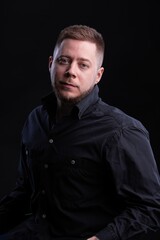 Obraz premium Strict and stylish Man in black shirt on dark background.