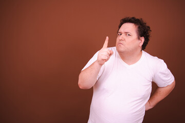 Funny fat man posing in the studio. Brown background.