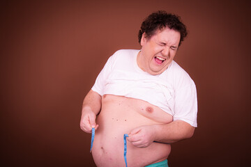Funny fat man posing in the studio. Brown background.