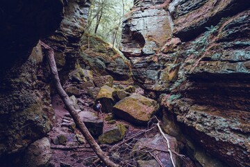 Woman hiker looking up at the rocks on her hike in the autumn woods