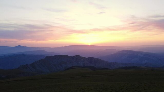 Picturesque dawn sunset sunrise mountain summit landscape bright sun sky horizon aerial static view. Drone shot cinematic darkness evening morning cliff rock scenery panorama colorful sunshine beams
