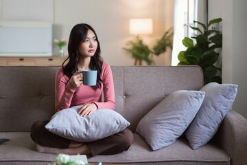 Women leisure on sofa to drinking coffee and looking outside enjoy with dreamy in lifestyle at home