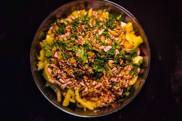 Bowl with vegetable salad on a black background