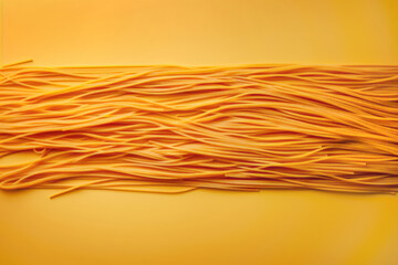 Strands of spaghetti pasta noodles stuck to a yellow background, throw spaghetti at the wall to see what sticks concept