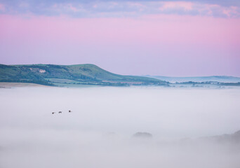 Misty morning sunrise from Wilmington Hill on the south downs east Sussex south east England UK