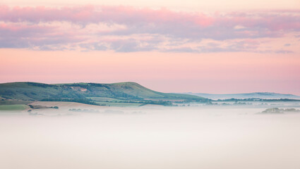 Misty morning sunrise from Wilmington Hill on the south downs east Sussex south east England UK