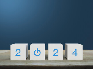 2024 start up business icon on white block cubes on wooden table over light blue wall, Happy new...