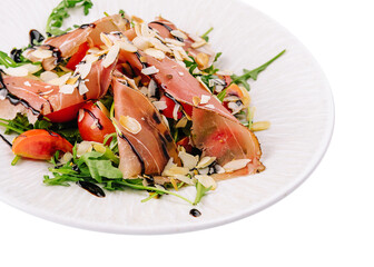 Salad with prosciutto, tomato, arugula leaves on plate