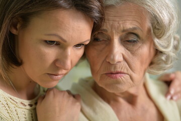 Portrait of sad Senior woman with daughter at home
