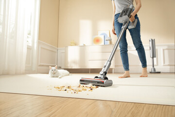 A woman is using a vacuum cleaner to clean a pet's room, dirty carpet and pet hair