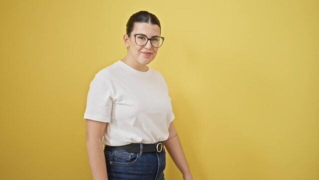 Young beautiful hispanic woman turning around smiling confident over isolated yellow background