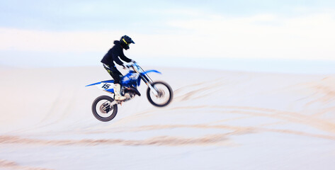 Sand, jump or athlete driving motorcycle for fitness, adventure or action with performance or...