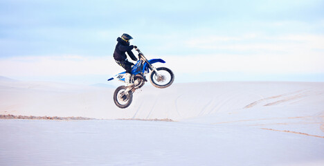 Desert, jump or person driving motorcycle for action, adventure or fitness with performance or adrenaline. Sand, risk or sports athlete on motorbike on dunes for training, exercise or race challenge