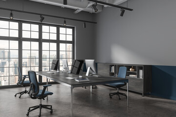 Dark office interior with pc monitors and sideboard, window. Mock up wall