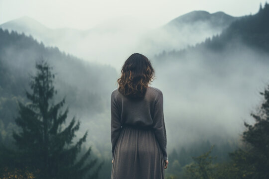 Back view of a sad woman standing alone in a misty morning, Shot in the mountain, soft light photography