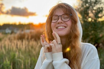 Portrait of happy young woman in glasses at sunset on natural background smile and looking at...