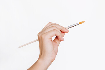 A female hand holding a paintbrush isolated on a white background. Mockup with empty copy space for text and design