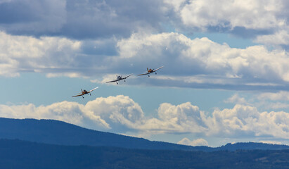 Three acrobatic plane flying on cloudy sky with mountain. Aviation, sport background
