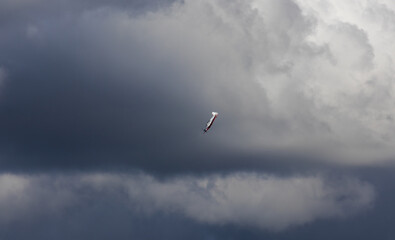 Acrobatic plane flying on dramatic cloudy sky from side. Aviation, sport background