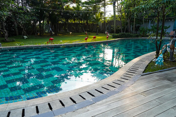 Blue water swimming pool and wooden deck, summer on a sunny day suitable for sports or relaxing on...
