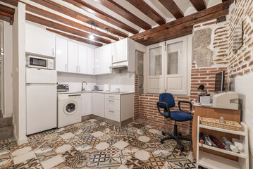 Open kitchen with white furniture and matching integrated appliances, wooden beamed ceiling