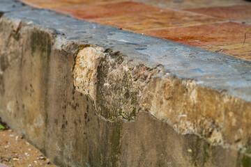 Partially collapsing old reinforced concrete curb, fence on border of roadway and hiking trail on...