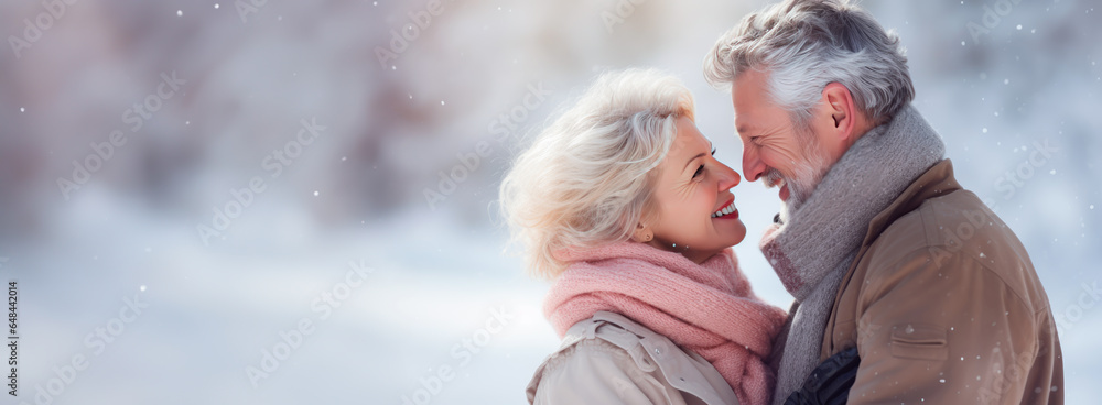 Wall mural senior couple in love holding each other close. snow falling around them, concept of wintertime and 